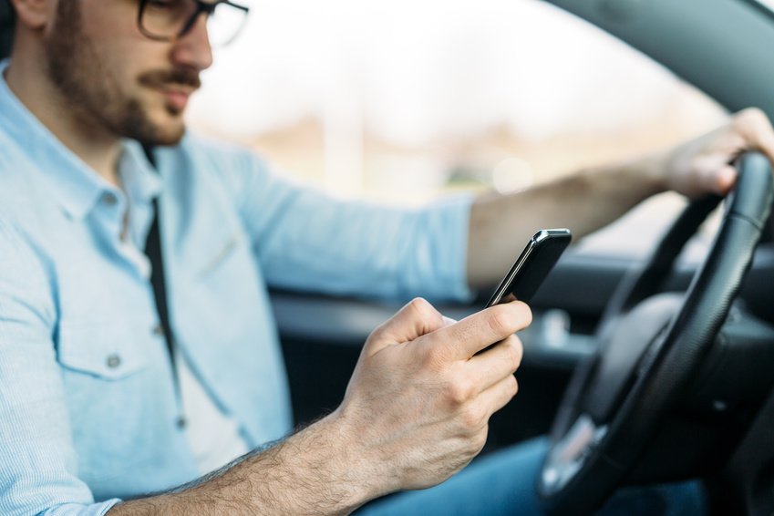 A man is texting while driving neglecting safety that might cause a car accident.
