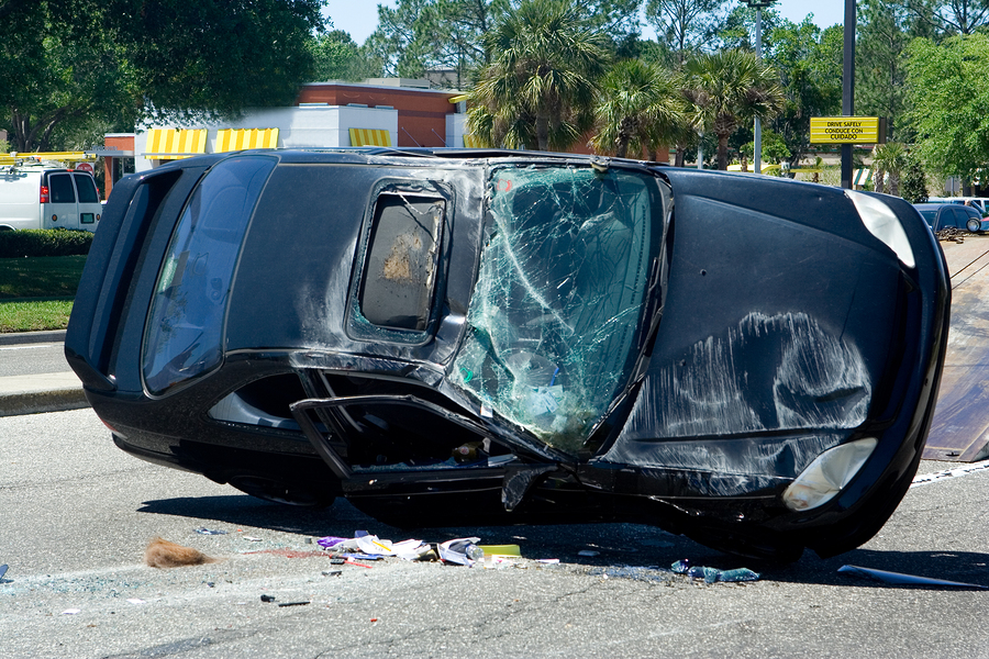 A black car had an accident was tilted on the road with broken window glass,