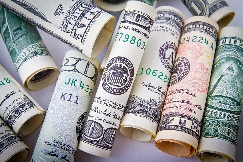 Group of different types of dollar bills that is being rolled separately and is placed on a white platform that is used on paying medical fees by the help of catastrophic injury lawyer.